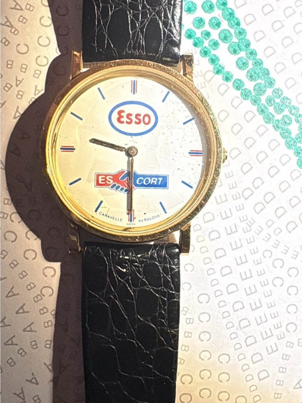 Caravelle by Bulova Gold-Tone Esso Logo Watch with Black Strap